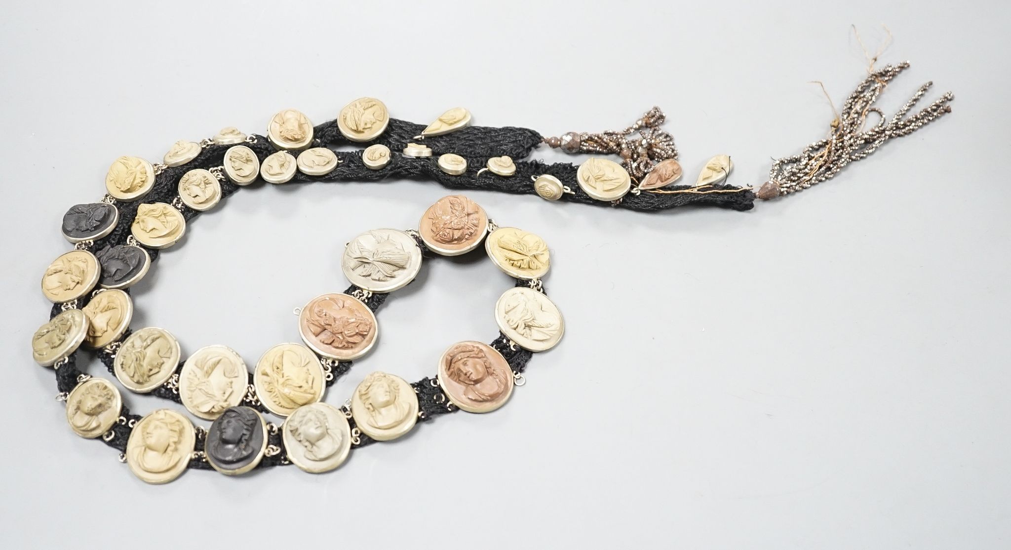 A group of graduated base metal mounted mainly oval lava cameos(thirty eight in total), mounted as on a sash necklace, with cut steel tassel terminals, length 115cm.